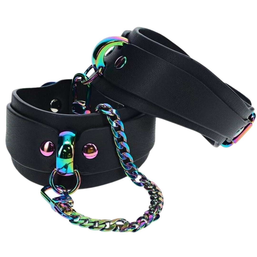 Black bonded leather ankle cuffs with iridescent rainbow hardware and a rainbow chain, designed for stylish BDSM restraint.