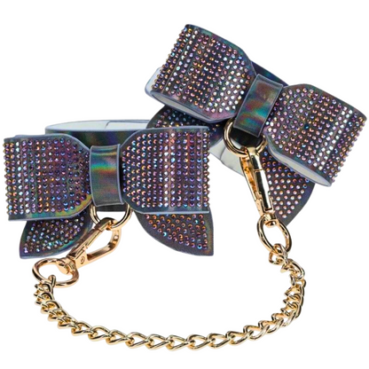 Adjustable ankle cuffs with rhinestone bows and gold chain leash, available in iridescent black, pink, and blue for stylish BDSM play.