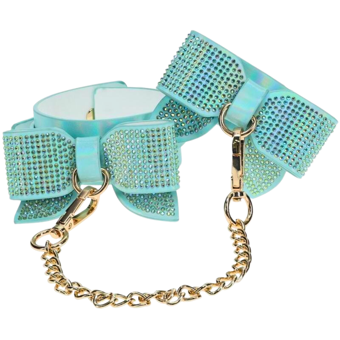 Adjustable ankle cuffs with rhinestone bows and gold chain leash, available in iridescent black, pink, and blue for stylish BDSM play.