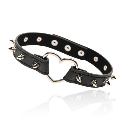 Spiked vegan leather collar with heart accent, adjustable snaps, and nickel-free hardware, available in light pink or black.