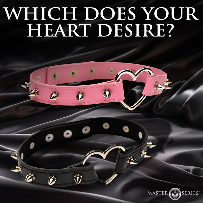 Spiked vegan leather collar with heart accent, adjustable snaps, and nickel-free hardware, available in light pink or black.