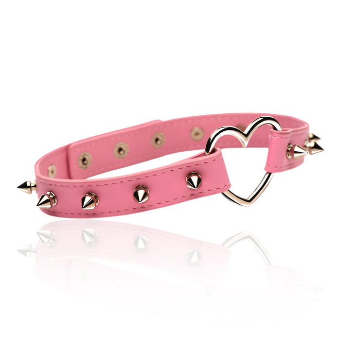 Spiked vegan leather collar with heart accent, adjustable snaps, and nickel-free hardware, available in light pink or black.