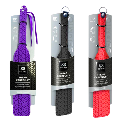 Double-sided spanking paddle with sleek smooth and tyre-textured surfaces, available in Black, Purple, and Red, featuring vegan materials and stylish design.

