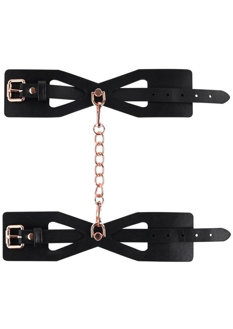 Sex and Mischief Brat Handcuffs - Black/Rose Gold Sportsheets S&M Brat Handcuffs with faux leather design, corset-like cutouts, and rose gold chain for stylish bondage play.