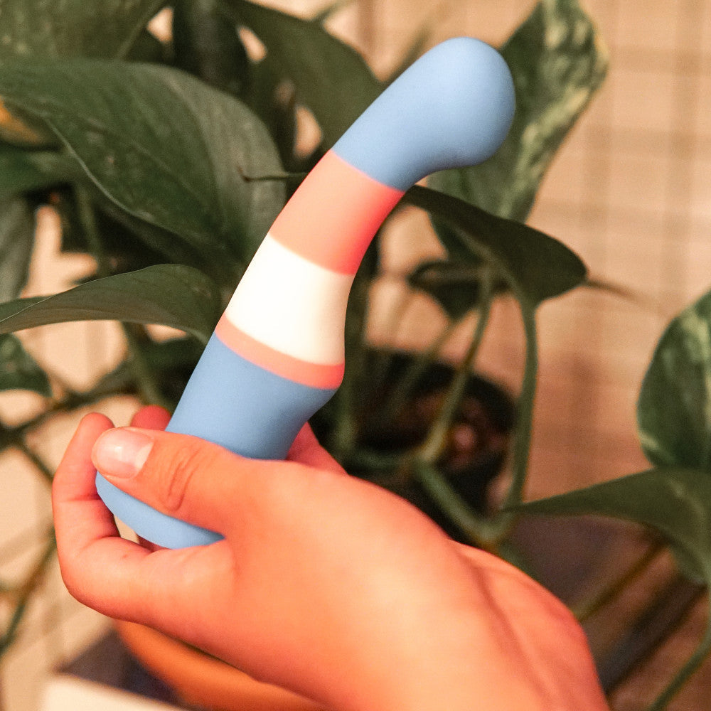 Trans pride flag-colored silicone dildo with a curved shaft, suction base, and smooth finish for G-spot or P-spot stimulation. Keywords: trans pride dildo, Avant dildo, G-spot dildo, P-spot dildo, suction cup dildo, harness-compatible dildo, body-safe silicone dildo, Purio silicone, colorful pride dildo, artisan-crafted dildo.